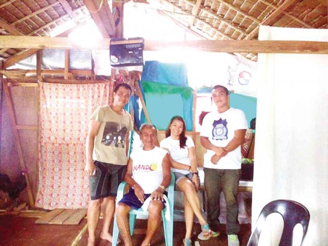 Rey Peñaranda, together with his ailing father, Santiago, and children Reymund and Cristine inside their newly repaired house made of light materials in Pampango District. The family, however, continues to live in a bunkhouse.  JOEY GABIETA