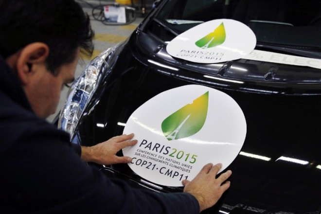 An employee puts a sticker which translates as "Paris 2015  Conference of the United Nations on Climate Change COP21-CMP11" on a electric Renault Nissan Leaf car on November 16, 2015 in Boulogne-Billancourt. France will be hosting and presiding the 21st Session of the Conference of the Parties to the United Nations Framework Convention on Climate Change (COP21/CMP11), also known as Paris 2015 from November 30 to December 11. AFP PHOTO/ PATRICK KOVARIK / AFP / PATRICK KOVARIK