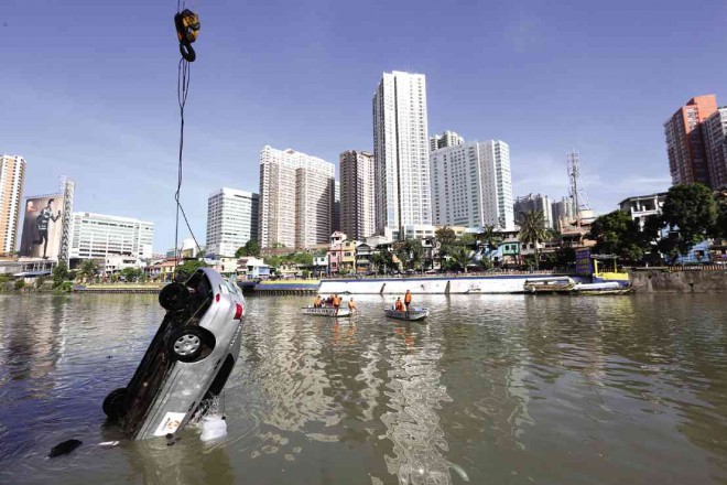 DEATH PLUNGE. The Meralco company car that fell into the Pasig River is pulled out of the water four hours after the Makati City incident on Saturday. The driver was killed while the passenger, a Meralco engineer, survived but remained under observation in a hospital. NIÑO JESUS ORBETA