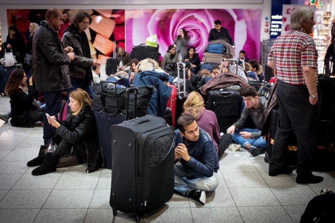 Travellers sit and wait at London's Gatwick Airport's North Terminal, Saturday Nov. 14, 2015, after the north terminal at Gatwick Airport was evacuated as a precaution after authorities found a suspicious article. Police described the evacuation Saturday as a precaution, but the incident comes at a time of heightened concern in Britain in the aftermath of the terror attacks in Paris. (Stefan Rousseau/PA via AP) UNITED KINGDOM OUT NO SALES NO ARCHIVE