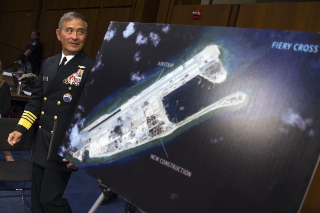 In this Sept. 17, 2015, file photo, Adm. Harry B. Harris, Jr., U.S. Navy Commander, U.S. Pacific Command walks past a photograph showing an island that China is building on the Fiery Cross Reef in the South China Sea, as the prepares to testify on Capitol Hill in Washington before the Senate Armed Services Committee hearing on maritime security strategy in the Asia-Pacific region. The U.S. Navy's challenge to China's sovereignty claims in the South China Sea was not designed as a military threat, Harris said Tuesday, Nov. 3, 2015, in a mostly upbeat speech about prospects for preventing U.S.-China disputes from escalating to conflict. Speaking in the Chinese capital, Harris cited a recent statement by U.S. Defense Secretary Ash Carter that the international order "faces challenges from Russia and, in a different way, from China, with its ambiguous maritime claims," including Beijing's claim to nearly all of the South China Sea. (AP Photo/Cliff Owen, File)