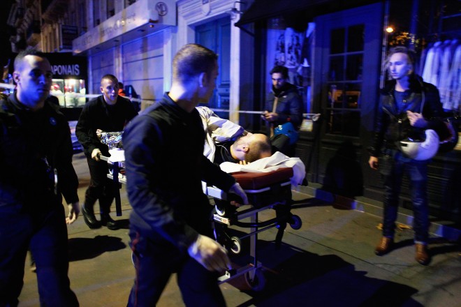 A person is being evacuated after a shooting, outside the Bataclan theater in Paris, Saturday, Nov. 14, 2015. A series of attacks targeting young concert-goers, soccer fans and Parisians enjoying a Friday night out at popular nightspots killed over 100 people in the deadliest violence to strike France since World War II.   (AP Photo/Thibault Camus)