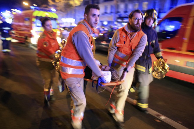 A woman is being evacuated from the Bataclan theater after a shooting in Paris, Friday Nov. 13, 2015.  French President Francois Hollande declared a state of emergency and announced that he was closing the country's borders. (AP Photo/Thibault Camus)