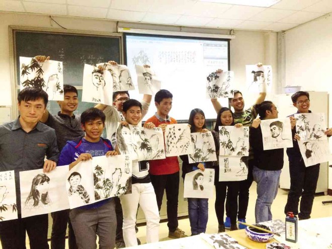 Showing off their paintings as teacher Liu Penghui looks on