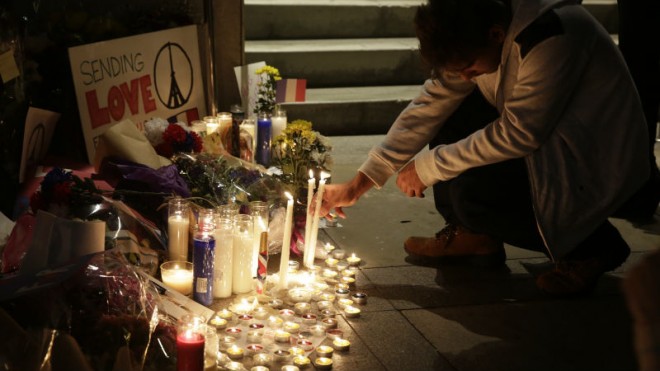 In this Saturday, Nov. 14, 2015, picture, people gather outside the French Consulate in Los Angeles to honor the victims of the Paris terrorist attacks. Multiple attacks across Paris on Friday night have left scores dead and hundreds injured. (AP Photo/Damian Dovarganes)