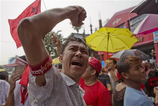Braving rain, a supporter of Myanmar's National League for Democracy party shouts slogans outside the NLD headquarters in Yangon, Myanmar, Monday, Nov. 9, 2015. Opposition leader Aung San Suu Kyi's NLD party was confident Monday that it was headed for a landslide victory in Myanmar's historic elections, as the democracy icon urged supporters not to provoke losing rivals who mostly represent the former junta that ruled this Southeast Asian nation for a half-century. (AP Photo/Gemunu Amarasinghe)