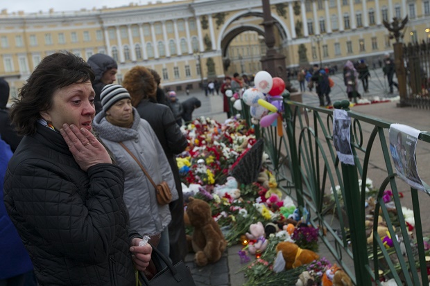 People look at photos of the plane crash victims attahced to the fence at Dvortsovaya (Palace) Square in St. Petersburg, Russia, on Monday, Nov. 2, 2015. In a massive outpouring of grief, thousands of people flocked to St. Petersburg's airport, laying flowers, soft toys and paper planes next to the pictures of the victims of the crash of a passenger jet in Egypt that killed all 224 on board in Russia's deadliest air crash to date. (AP Photo/Ivan Sekretarev)