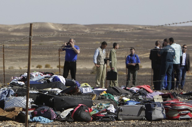 Russian investigators stand near debris, luggage and personal effects of passengers a day after a passenger jet bound for St. Petersburg in Russia crashed in Hassana, Egypt, on Sunday, Nov. 1, 2015. The Metrojet plane crashed 23 minutes after it took off from Egypt's Red Sea resort of Sharm el-Sheikh on Saturday morning. The 224 people on board, all Russian except for four Ukrainians and one Belarusian, died. (AP Photo/Amr Nabil)