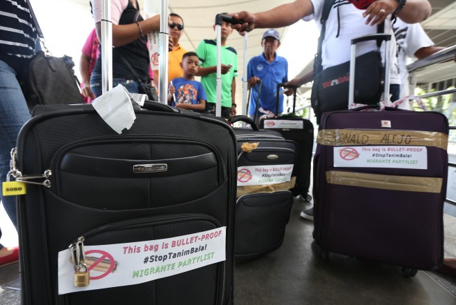 November 3, 2015 Stickers bearing Stop Tanim Bala warnings are handed out to passengers entering the NAIA Terminal 2, in Pasay City, by militant group Migrante to discourage anyone from planting bullets in their baggages. INQUIRER/ MARIANNE BERMUDEZ
