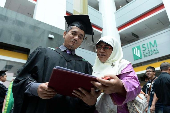 Mr Mohamed Ali N. Sarwar, 43, with his mother, Madam Fathimah Abdullah, 64, after the UniSIM convocation ceremony on Oct 7. Mr Ali, a firm believer in lifelong learning, earned a degree in building and project management.ST PHOTO: DESMOND FOO