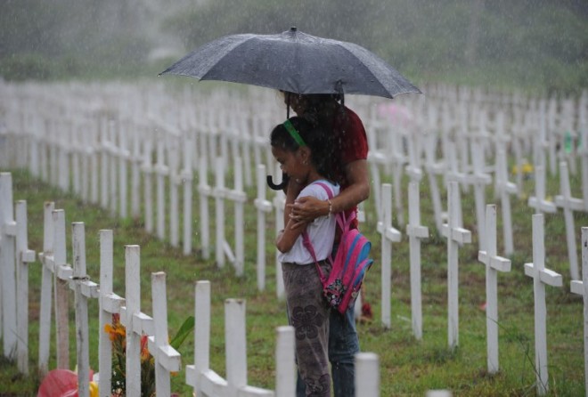 A mother and her daughter brave heavy rains as they visit graveyard of their loved ones at the mass grave for victims of typhoon Haiyan, during the traditional visit to family graveyards in Tacloban City, Leyte province, central Philippines on November 1, 2015. Millions of the people in the Philippines made their annual pilgrimage to their family gravesites on November 1, in a tradition that is part Catholic ritual and part love of festivity, and recent tragedies like super typhoon Haiyan are a sharp reminder of the constant danger to life in this disaster-plagued nation.   AFP PHOTO / TED ALJIBE
