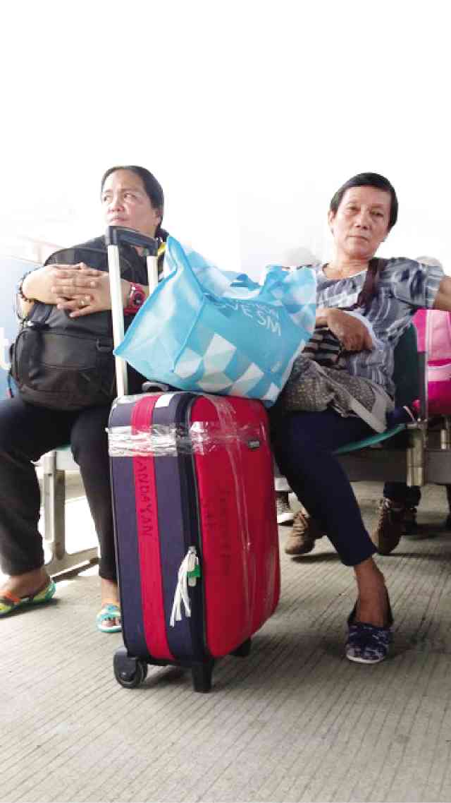 Aside from being padlocked and zipped up, plane passenger Cynthia Velasquez’s (right) bag is secured by a transparent packaging tape at Tagbilaran City airport. Velasquez admitted it is a measure against “tanim-bala,” the extortion racket victimizing travelers at Ninoy Aquino International Airport. LEO UTDOHAN/INQUIRER VISAYAS