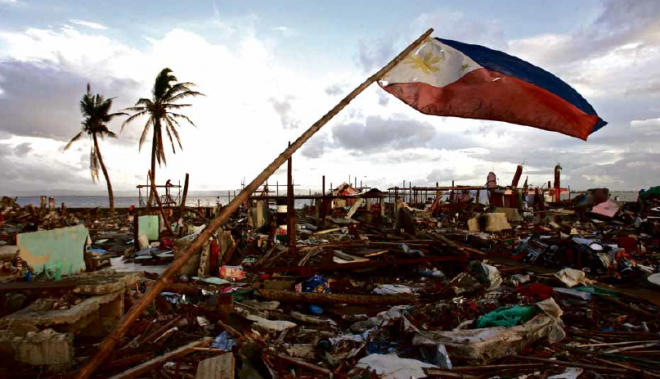 ‘WE’RE STILL HERE’ A Philippine flag flutters in the wind from a near-fallen bamboo pole in Tacloban City, signifying the residents’ resilience after the devastation caused by Supertyphoon “Yolanda.” RAFFY LERMA