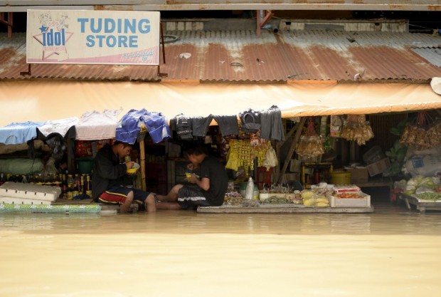 Vendors eat their lunch as they wait for customers at a flooded market in Candaba, Pampanga, north of Manila on December 18, 2015. Vast swathes of farmlands inundated by Typhoon Koppu in October were flooded again this week by rains from Typhoon Melor and the flooding could worsen or spread to other areas as a second storm in less than a week threatens the country.  AFP PHOTO / NOEL CELIS / AFP / NOEL CELIS