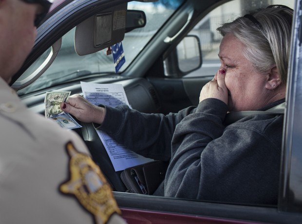 Deborah Beach, of Bowling Green,, Ky., reacts after Sheriff's Deputy Chris Shelton gave her a $100 bill after pulling her over on Louisville Road, Wednesday, Dec. 9, 2015, in Bowling Green, Ky. An anonymous donation to the Warren County Sheriff's Office provided the funds. (Austin Anthony/Daily News via AP) MANDATORY CREDIT