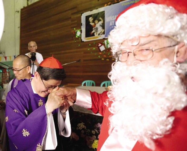 CHRISTMAS WISHES  Even Archbishop Luis Antonio Cardinal Tagle (center) needs a Santa Claus, if only to help underprivileged children (left photo) get what they want for Christmas. Their wishes were written on white balloons that were later blessed by the cardinal.  Tagle and Santa met the children at a pre-Christmas event at Pamantasan ng Lungsod ng Maynila on Friday. PHOTOS BY MARIANNE BERMUDEZ 