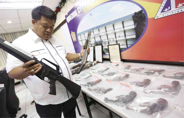 FROM CAMP CRAME’S BACKYARD Supt. Jay Agcaoili, head of the QCPD’s special operations unit, shows the firearms found by his men at a house that allegedly provided cover for a gunrunning syndicate operating just outside the general headquarters of the Philippine National Police. NIÑO JESUS ORBETA