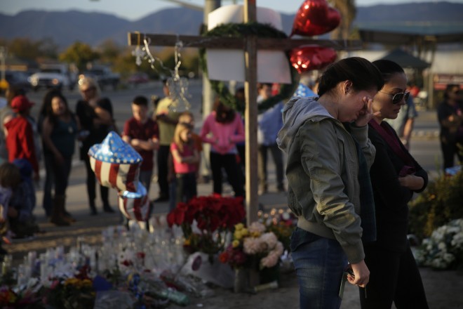 Yanira Perez, second from right, wipes her eyes as she and her mother, Marcela, pay respects at a makeshift memorial to honor the victims of Wednesday's shooting rampage, Saturday, Dec. 5, 2015, in San Bernardino, Calif. The Pakistani woman who joined her U.S.-born husband in killing multiple people in a commando-style assault on his co-workers is at the center of a massive FBI terrorism investigation, yet she remains shrouded in mystery. (AP Photo/Jae C. Hong)