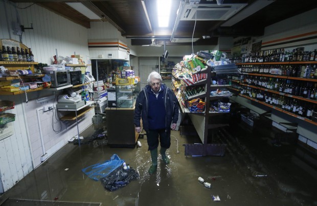 A shopkeeper looks at the damage caused by the swollen waters of the River Beck in the Cumbrian village of Glenridding in northwest England after the river burst its banks for the second time since the weekend following overnight heavy rain Thursday Dec.10, 2015.  (Danny Lawson/PA via AP) UNITED KINGDOM OUT  NO SALES NO ARCHIVE