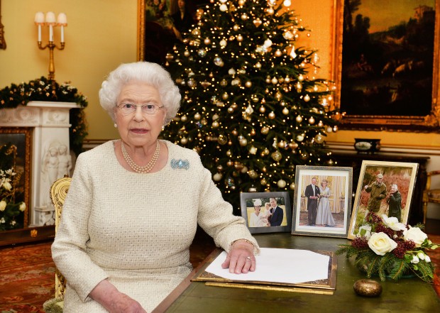 In this Dec. 10, 2015 photo, Britain's Queen Elizabeth II sits at a desk in the 18th Century Room in Buckingham Palace in London, after recording her Christmas Day broadcast to the Commonwealth, to be broadcast Friday, Dec. 25, 2015.  Pictures on the desk are members of the Royal family, from right, Queen Elizabeth with Duke of Edinburgh,  Prince Charles with Camilla Duchess of Cornwall, and Prince William with Kate and their children Prince George and Princess Charlotte. AP
