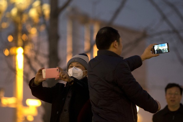 A man wears a mask to protect against the pollution as he takes a selfie in Beijing, China, Wednesday, Dec. 9, 2015. Unhealthy smog hovered over downtown Beijing as limits on cars, factories and construction sites kept pollution from spiking even higher Wednesday, on the second of three days of restrictions triggered by the city's first red alert for smog. (AP Photo/Ng Han Guan)