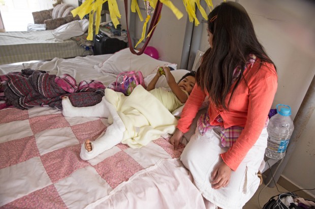 In this Dec. 15, 2015, photo, Marleny Gonzalez, right, looks at her 4-year-old daughter, Jenifer, at a shelter in Reynosa, Mexico, where they are living after trying to cross in to the United States. Gonzalez said her daughter suffered two broken legs when a truck they were traveling in overturned on the journey from Guatemala. “Almost all my family is in the United States,” Gonzalez said, including her daughter’s father. “I felt alone," she said. Given her daughter’s precarious state, she wasn’t sure whether she would make the rest of the trip. (AP Photo/Seth Robbins)