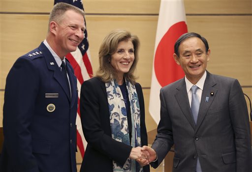 FILE - In this Dec. 4, 2015 file photo, U.S. Ambassador to Japan Caroline Kennedy, center, accompanied by Lt. Gen. John Dolan, left, commander of U.S. Forces Japan, shakes hands with Japanese Chief Cabinet Secretary Yoshihide Suga after their joint press conference at Japan's Prime Minister's official residence in Tokyo. Kennedy on Thursday, Dec. 17 publicly defended a controversial proposal to relocate a U.S. Marine Corps base on Okinawa in southern Japan as the best of many options considered. (AP Photo/Koji Sasahara, Pool, File)