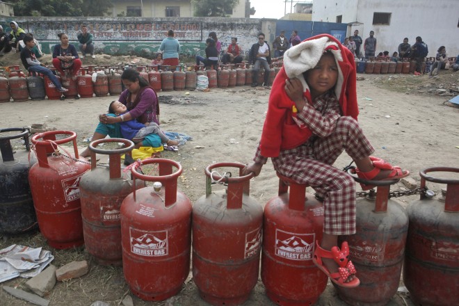 Nepalese people sit near empty cooking gas cylinders lines as they wait for fresh supply in Kathmandu, Nepal, Monday, Nov. 16, 2015. Nepal's prime minister Khadga Prasad has asked neighboring India to lift an "undeclared blockade," saying the Himalayan nation is facing a severe fuel shortage and trouble obtaining medicine and food supplies blocked at the border. (AP Photo/Niranjan Shrestha)