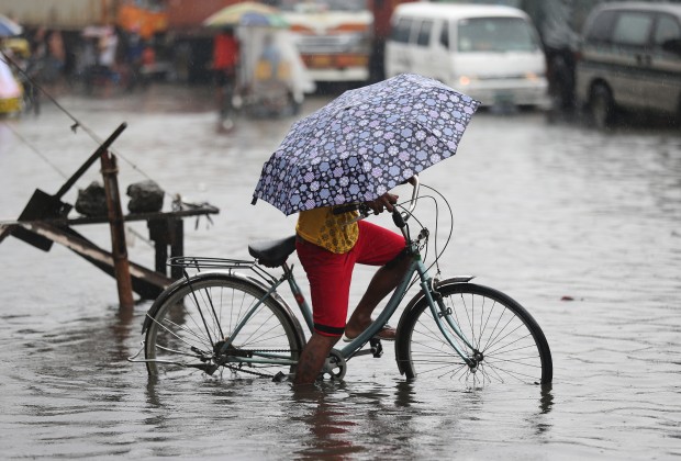 A Filipino tries to bike along a flooded street caused by heavy rains from Typhoon Melor in suburban Navotas, north of Manila, Philippines on Wednesday, Dec. 16, 2015. Typhoon Melor left at least one person dead and wide areas without power Tuesday as it crossed over the central Philippines.(AP Photo/Aaron Favila)