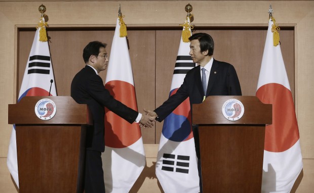 South Korean Foreign Minister Yun Byung-se, right, shakes hands with his Japanese counterpart Fumio Kishida after their joint press conference at Foreign Ministry in Seoul, South Korea, Monday, Dec. 28, 2015. The foreign ministers said they had reached a deal meant to resolve a decades-long impasse over Korean women forced into Japanese military-run brothels during World War II, a potentially dramatic breakthrough between the Northeast Asian neighbors and rivals. (AP Photo/Ahn Young-joon)