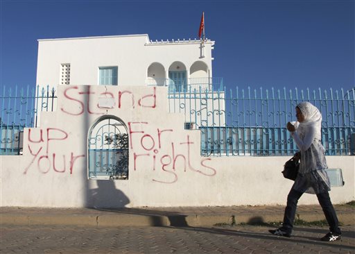 In this Oct. 19, 2011, file photo, a woman walks past electoral graffiti in Sidi Bouzid, Tunisia. Tunisians who won the Nobel Peace Prize join with townspeople in the country's beleaguered heartland on Thursday, Dec. 17, 2015, to mark five years since a desperate street vendor set himself on fire, unwittingly setting in motion upheaval across the Arab world. (AP Photo/Aimen Zine, File)