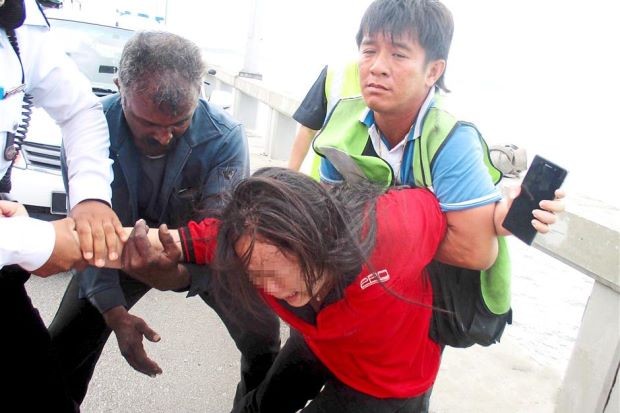 In the nick of time: Ah Heong (right) restraining the woman who attempted to commit suicide along the Penang Bridge. THE STAR/ANN