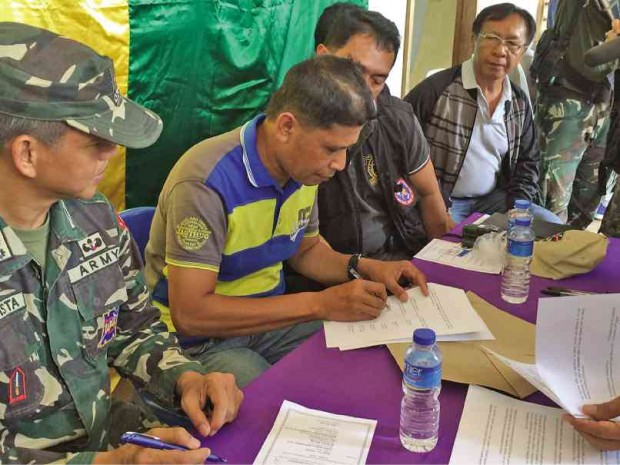 MILF’s 114th Base Command commander Dan Asnawi signs  a document committing to work with the military, local government and International Monitoring Committee to secure the liberated communities from the Abu Sayyaf Group. 