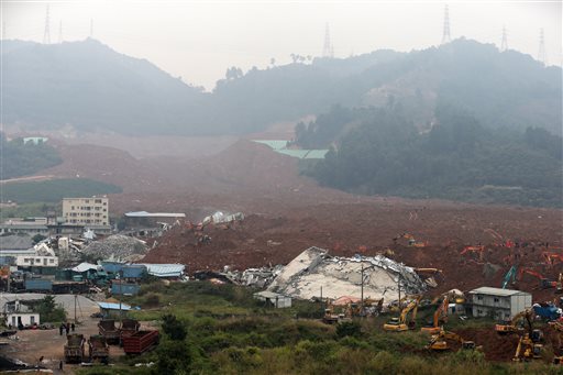 Rescuers search for potential survivors near collapsed buildings following a landslide in Shenzhen, in south China's Guangdong province, Monday, Dec. 21, 2015. A mountain of excavated soil and construction waste buried dozens of buildings when it swept through an industrial park Sunday. (AP Photo/Andy Wong)