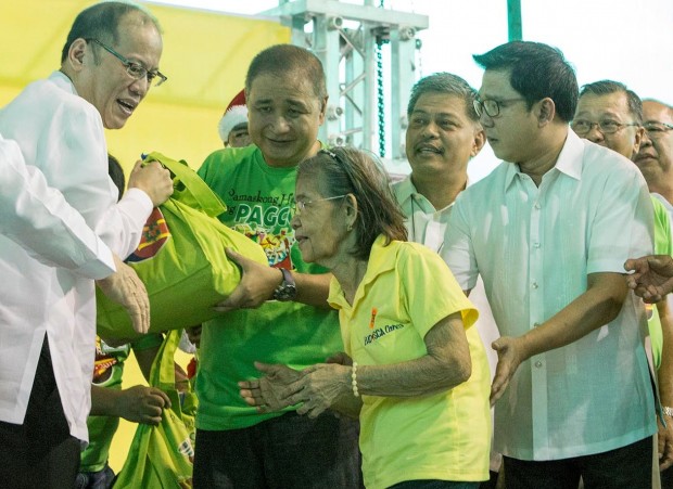 President Benigno S. Aquino III (left) and PAGCOR Chairman and CEO Cristino L. Naguiat, Jr.  (2nd from left) hand over a Christmas gift pack to one of the senior citizens of Quezon City during  the state-run gaming firm’s gift-giving event. Also in photo are DepEd Secretary Bro. Armin  Luistro (2nd from right), Quezon City Mayor Herbert Bautista and other local officials of Quezon  City. More than 3,100 street sweepers, members of the tricycle drivers and operators association  (TODA) and senior citizens from Quezon City received noche buena gift packs fom the  Philippine Amusement and Gaming Corporation (PAGCOR) during the agency' Pamaskong  Handog gift-giving held in Quezon City Memorial Circle on December 14, 2015. 