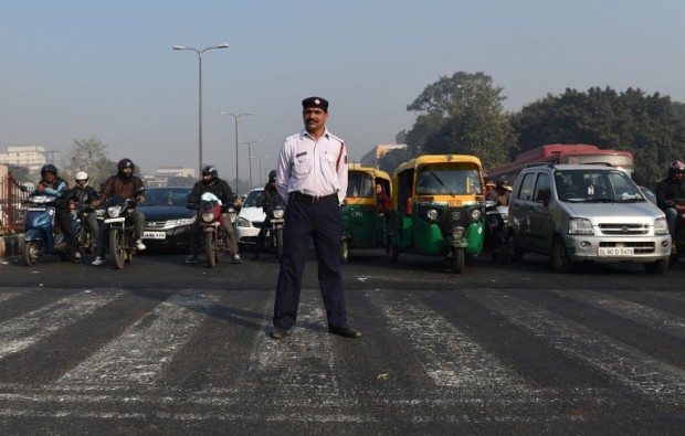 An India traffic policeman stands at a traffic intersection in New Delhi on December 31, 2015. Millions of Delhi residents will have to find alternative ways to work from January 1, 2016, when authorities impose draconian restrictions on cars to try to clean up the world's most polluted capital. Private cars will be banned from the roads on alternate days, apart some exceptions such as those that run on CNG, from January 1 as part of a slew of measures aimed at reducing smog levels that include shutting some coal-fired power plants and vacuuming roads to reduce dust. AFP PHOTO / Money SHARMA / AFP / MONEY SHARMA