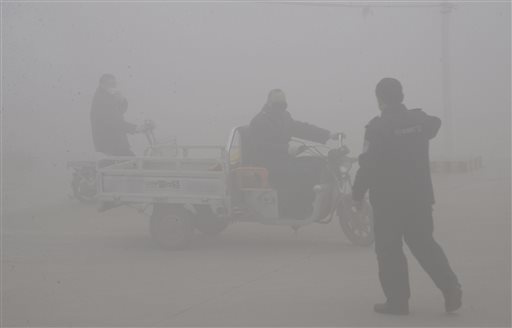 A policeman talks to the driver of a motor-tricycle on a road amid heavy haze in Handan city in northern China's Hebei province Thursday, Dec. 24, 2015. Meteorological authorities in Hebei, a province which neighbors Beijing and is regarded as China's most polluted, issued its first red alert for smog on Tuesday as more Chinese cities are issuing their first red alerts for pollution in response to forecasts of heavy smog. (Chinatopix via AP) CHINA OUT