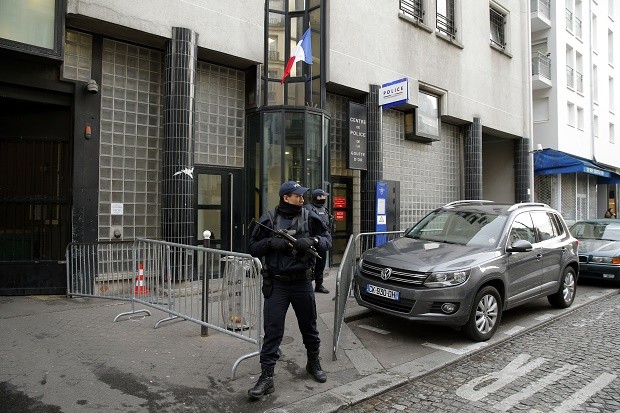 Police stand guard in front of the police station where a man was killed Thursday after he showed up wearing fake explosives, in Paris, Friday, Jan. 8, 2016.  A French security official says initial probes have identified the man as a 20-year-old Moroccan previously involved in a minor robbery in the southern Var region. (AP Photo/Christophe Ena)