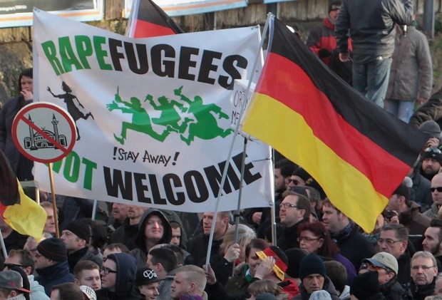 Right-wing demonstrators hold a sign "Rapefugees not welcome - !Stay away!" and a sign with a crossed out mosque as they march in Cologne, Germany Saturday Jan. 9, 2016. Women’s rights activists, far-right demonstrators and left-wing counter-protesters all took to the streets of Cologne on Saturday in the aftermath of a string of New Year’s Eve sexual assaults and robberies in Cologne blamed largely on foreigners. (AP Photo/Juergen Schwarz)