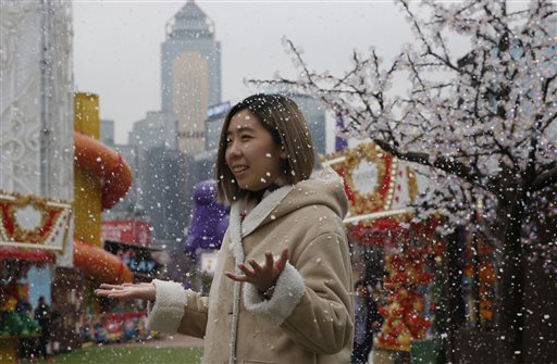 A visitor enjoys the artificial snow made of foam at a carnival in Hong Kong, Tuesday, Jan. 26, 2016. In Hong Kong, the mercury dipped to its lowest in six decades. Many were also hoping to see snow after rumors started circulating on social media that it was on the way, but the government dismissed the reports. (AP Photo/Kin Cheung)