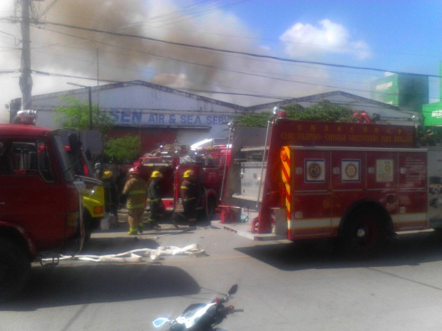 Firefighters try to put out the fire that hit two warehouses on Arellano St., Barangay San Roque, Cebu City. Photo by Jhunnex Napallacan, Inquirer Visayas
