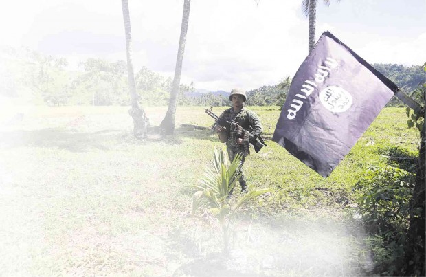 A MARINE walks past an Isis flag in a Moro rebel camp that government soldiers captured in the town of Palimbang in Sultan Kudarat province in November 2008.JEOFFREY MAITEM /INQUIRER MINDANAO