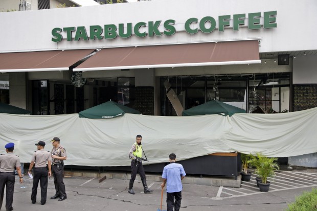 Police and officials gather in the parking lot outside the damaged Starbucks cafe where Thursday's attack occurred in Jakarta, Indonesia, on Friday, Jan. 15, 2016. A day after attackers detonated bombs and engaged in gunbattles with police in the central part of Indonesia’s capital, Jakarta tried to get itself back on track. (AP Photo/Tatan Syuflana)