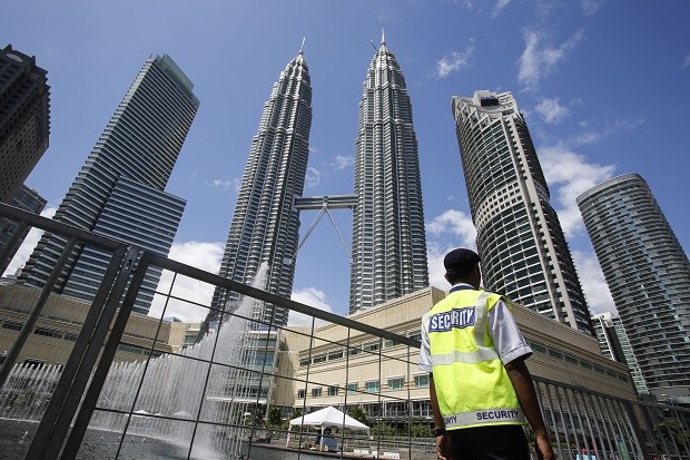 A security guard patrols in front of Malaysia's landmark buildings, Petronas Twin Towers, ahead of the New Year's celebration in Kuala Lumpur, Malaysia, Thursday, Dec. 31, 2015. Security has been beefed up in Malaysia's biggest city, Kuala Lumpur, where fireworks will ring in the new year at a historical square as well as at the Petronas Twin Towers, one of the world's tallest towers. Malaysian authorities have detained more than 120 suspects linked to the Islamic State group over the past two years, some of whom were allegedly plotting to launch attacks in strategic areas of Kuala Lumpur. (AP Photo/Joshua Paul)