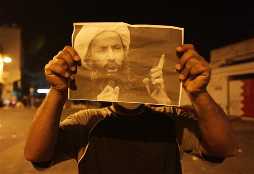 In this Wednesday, Oct. 15, 2014, file photo, a Bahraini anti-government protester holds up a picture of jailed Saudi Sheik Nimr al-Nimr during clashes with riot police in Sanabis, Bahrain, a suburb of the capital Manama.  Saudi Arabia says it has executed 47 prisoners, including leading Shiite cleric Sheikh Nimr al-Nimr. The cleric’s name was among a list of the 47 prisoners executed carried by the state-run Saudi Press Agency. It cited the Interior Ministry for the information. (AP Photo/Hasan Jamali, File)