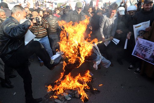Followers of Shiite cleric Muqtada al-Sadr burn an effigy of King Salman of Saudi Arabia as they hold posters of Sheik Nimr al-Nimr during a demonstration in Baghdad, Iraq, Monday, Jan. 4, 2016. Demonstrations are also being called for in the predominantly Shiite southern cities of Najaf and Basra, after Saudi Arabia executed a prominent opposition Shiite cleric convicted of terrorism charges, sparking anger in Iran and among Shiites across the region. (AP Photo/Khalid Mohammed)