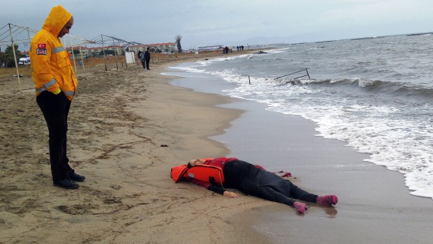 A Turkish rescue worker looks at the body of a migrant lying on the beach in Ayvalik, Turkey, Tuesday, Jan. 5, 2016. A Turkish media report says the bodies of seven more migrants have washed up on a shore in Turkey _ in a second migrant tragedy at sea in one day. The Dogan news agency the drowned bodies, including women and children, washed up at the coast of Dikili on Tuesday, hours after nine bodies were discovered further north, on a sandy beach in the resort of Ayvalik. Dikili and Ayvalik _ some 50 kilometers (30 miles) away _are crossing points for migrants trying to make their way to the Greek island of Lesbos.(AP Photo)