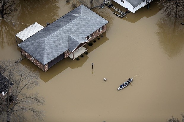 In this aerial photo, people use a canoe to navigate a flooded street, Thursday, Dec. 31, 2015, in Arnold, Mo. Surging Midwestern rivers forced hundreds of evacuations, threatened dozens of levees and brought transportation by car, boat or train to a virtual standstill Thursday in the St. Louis area. (AP Photo/Jeff Roberson)