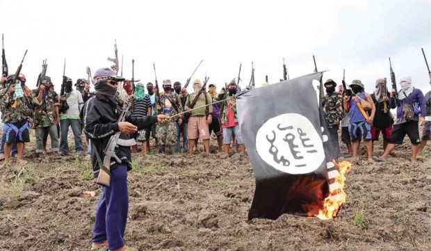 Members of an erstwhile unknown group calling itself “Red God Soldiers” burn a replica of an Isis flag on the day they announced their existence somewhere in Central Mindanao. JEOFFREY MAITEM/INQUIRER MINDANAO