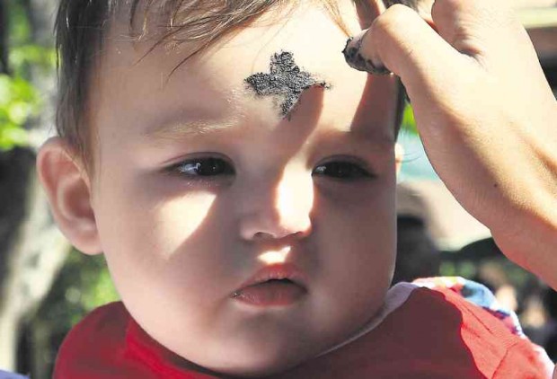 NEVER TOO YOUNG A lay minister at Baclaran Church marks the forehead of a toddler with the sign of the cross using ashes from burnt palm fronds, as part of the observance of Ash Wednesday which marks the start of Lent.  EDWIN BACASMAS